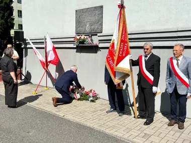 Znicze i biało-czerwone wieńce pod tablicą pamięci o Wołyniu